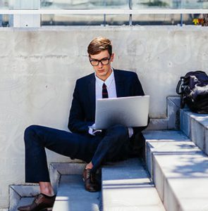 Man in Blue Suit Using His Laptop on Stairs